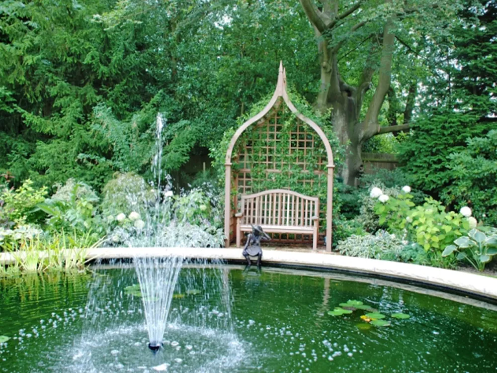 arbour and bench overlooking a pond in a garden